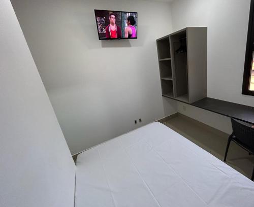 a white room with a bed and a desk at NANO Suítes - solteiro in Uberlândia