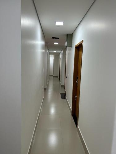 a long hallway with white walls and a door at NANO Suítes - solteiro in Uberlândia