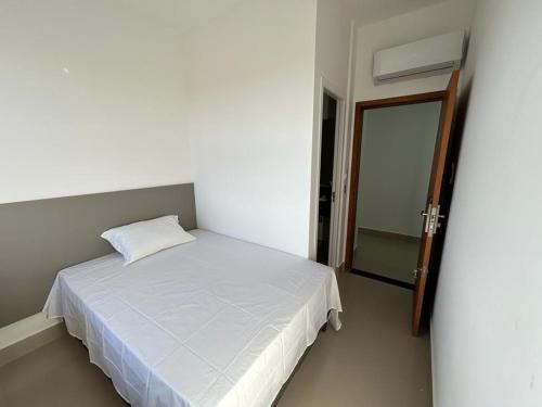 a small bedroom with a white bed and a door at NANO Suítes - solteiro in Uberlândia