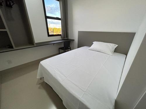 a white bed in a room with a window at NANO Suítes - solteiro in Uberlândia