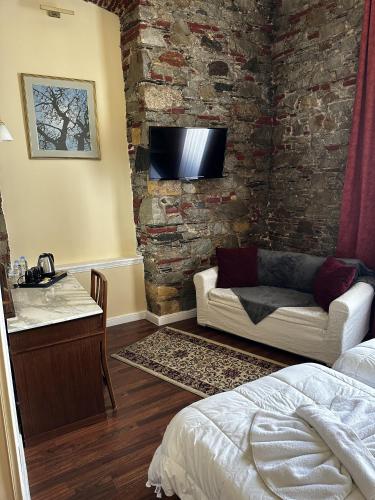 - une chambre avec un canapé et une télévision sur un mur en briques dans l'établissement Hotel Aktaion Syros, à Ermoúpoli