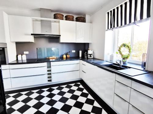eine Küche mit weißen Schränken und einem karierten Boden in der Unterkunft Haus am Deich 47 stilvolles Landhaus an der Elbe in Stadtnähe in Hamburg
