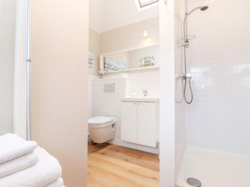 a white bathroom with a shower and a toilet at Canny Cottage in Morpeth