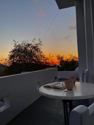 a table on a balcony with a sunset in the background at Galanos Katoikies in Órmos Aiyialís