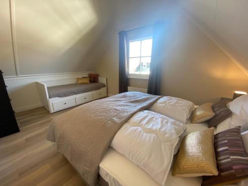 Schlafzimmer mit einem Bett, einem Fenster und einer Bank in der Unterkunft Villa Stilleven in Callantsoog