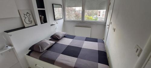 Dormitorio pequeño con cama con motivos de tablero de ajedrez en Nice and Sweet Apartment - self check in, en Zagreb
