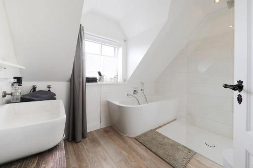 een witte badkamer met een bad en een wastafel bij Haus am Deich 47 stilvolles Landhaus an der Elbe in Stadtnähe in Hamburg