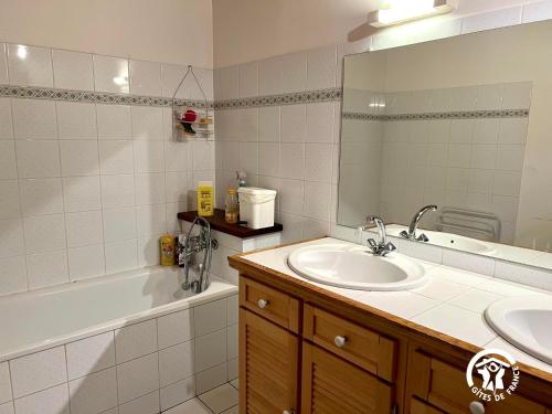 een badkamer met een wastafel, een bad en een spiegel bij Cabanat in Belvis