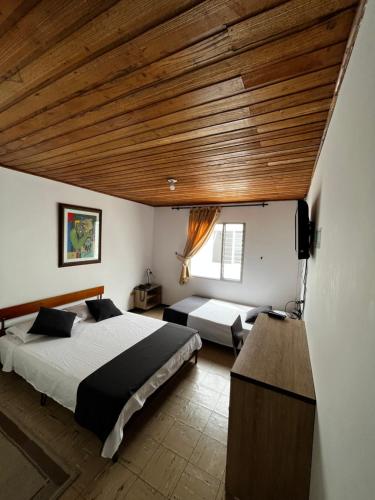 a bedroom with two beds and a wooden ceiling at Hotel Alpino in Armenia