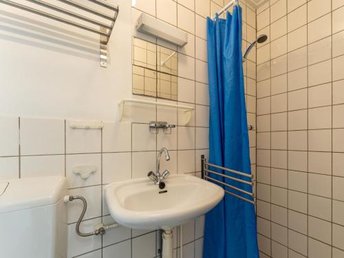 a bathroom with a sink and a blue shower curtain at Modern holiday home in Baarland with terrace in Baarland