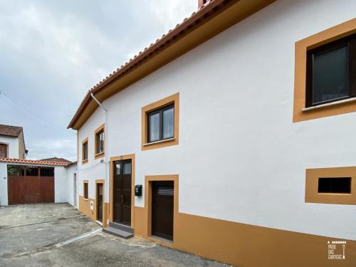 een wit huis met bruine ramen en een oprit bij Pátio das Cantigas in Góis