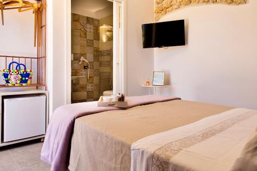 a bedroom with a bed and a tv on the wall at Oikos in Terre di Zaccanello in Racalmuto