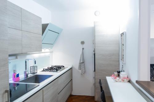 SWEET HOUSE CORSO GENOVA في ميلانو: مطبخ مع دواليب بيضاء ومغسلة