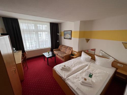 um quarto de hotel com uma cama e um sofá em Hotel Poseidon em Kühlungsborn