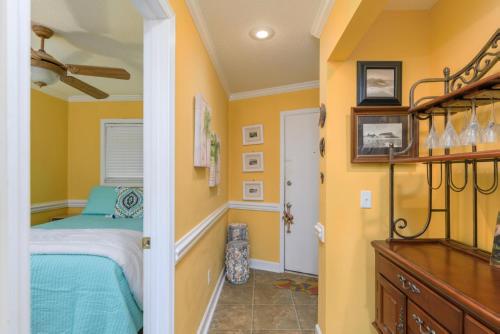 a bedroom with yellow walls and a bed and a dresser at Love Shack in Tybee Island