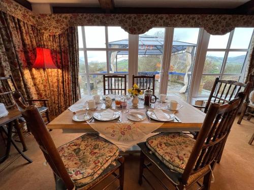 a dining room table with chairs and a large window at Pentre Cerrig Country House in Llanferres