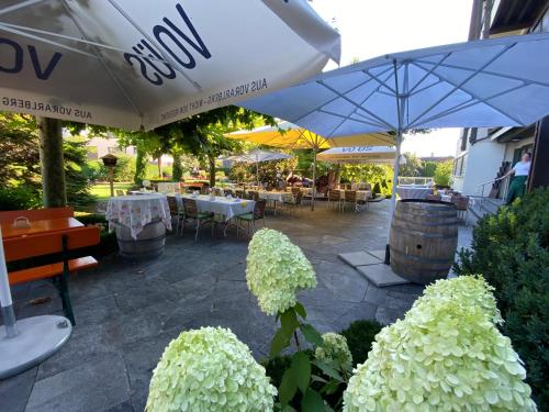 a patio with tables and umbrellas with white flowers at Hotel Restaurant Rössle in Rankweil
