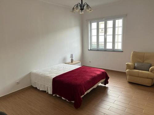 a bedroom with a bed and a chair and a window at Casa da Luz in Angra do Heroísmo