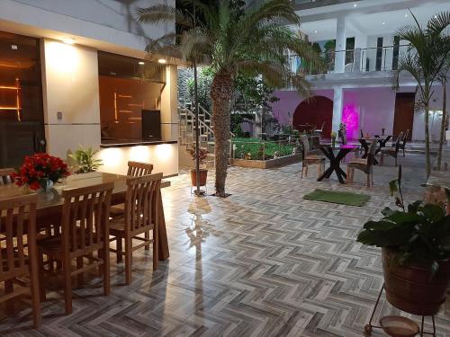 restauracja ze stołami, krzesłami i palmami w obiekcie La Posada 815 w mieście Pisco