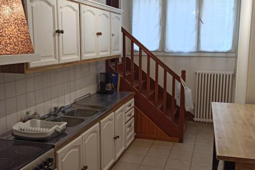 - une cuisine avec des placards blancs, un évier et un escalier dans l'établissement Petite maison de bourg proche A84, à Ducey