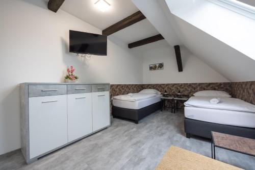 a room with two beds and a tv on the wall at Penzion Rozhovice in Rozhovice