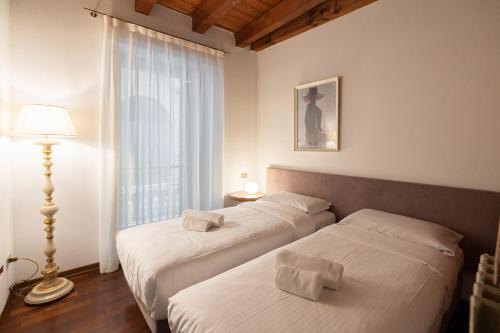 1 dormitorio con 2 camas, lámpara y ventana en Domus Verona - Centralissima e antica Residenza Cappello, en Verona