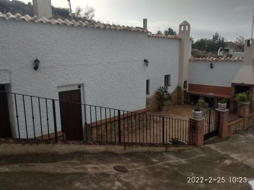 a white building with a fence in front of it at CASA CUEVA VANESA in Hinojares