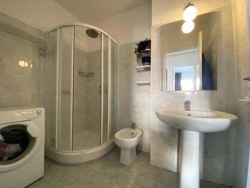 La salle de bains est pourvue d'un lavabo, d'une douche et d'un lave-linge. dans l'établissement Le Garavan-vue mer-plage-clim-terrasse, à Menton