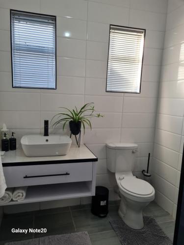 a white bathroom with a toilet and a sink at Egerton Overnight & Stay in Kimberley