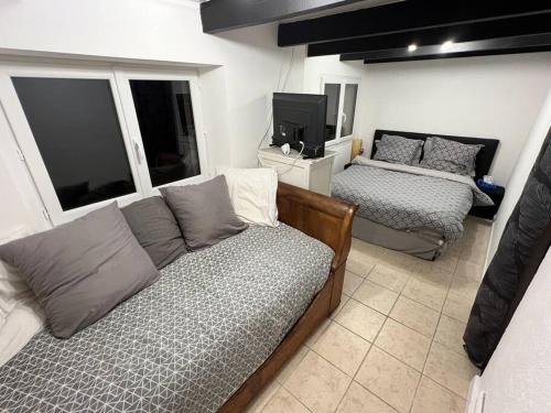 a living room with two beds and a tv at Charmante maison berrichonne in Gargilesse-Dampierre