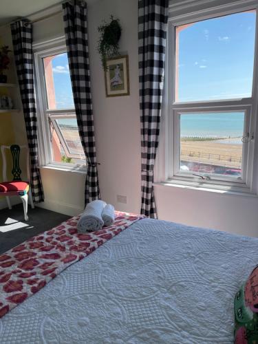 1 dormitorio con 1 cama y 2 ventanas con vistas en "The Parlour" Seafront Apartment, en Eastbourne