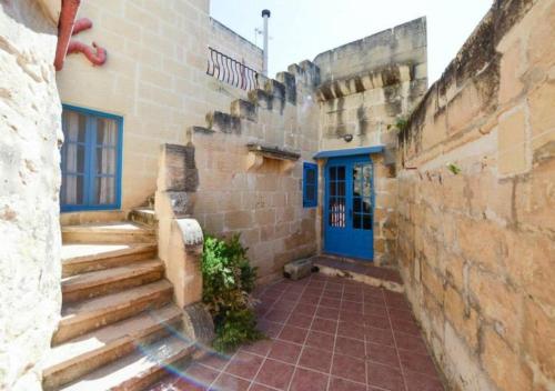 un edificio de piedra con una puerta azul y escaleras en Tan-Nahla (128B) Holiday Farmhouse with Private Pool en Il-Pergla