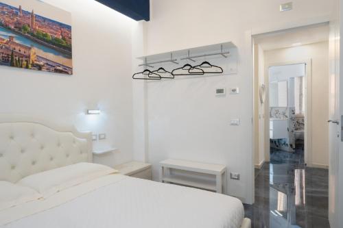 a white bedroom with a bed and a pair of sunglasses on the wall at Residenza Elisabetta in Verona