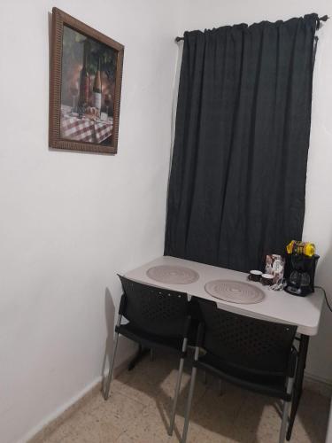 una mesa con dos sillas y una cortina negra en Hermoso Apartamento frente Aeropuerto de Isla Verde, en San Juan