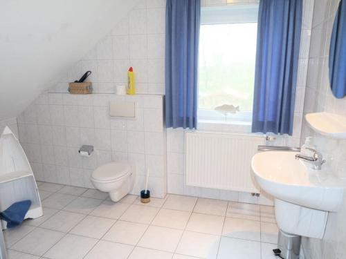 a white bathroom with a toilet and a sink at Muschel 2 in Bensersiel