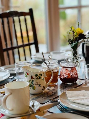 a wooden table with plates and cups on it at Pentre Cerrig Country House in Llanferres