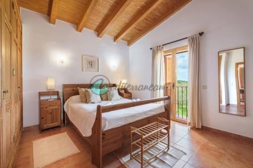 a bedroom with a bed and a large window at Ecovilla ses oliveres by villasmediterranean in Llubí