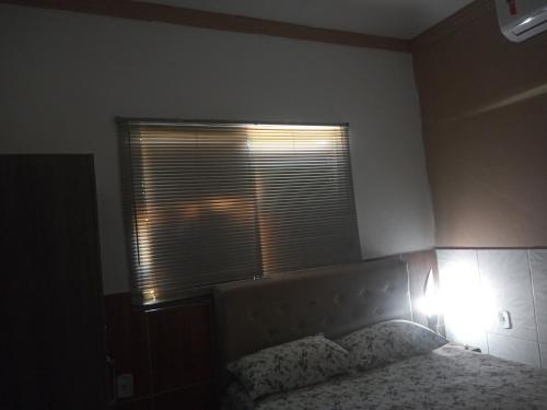a bedroom with a bed and a window with a light at Cantinho Nativus in Maragogi