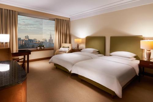 a hotel room with two beds and a large window at Regent Warsaw Hotel in Warsaw