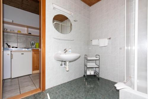 La salle de bains blanche est pourvue d'un lavabo et d'un miroir. dans l'établissement Williams Haus, à Hévíz