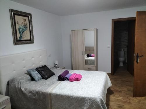 a bedroom with a white bed with pink pillows at LA POSAINA in Serradilla