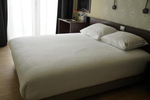 ein Bett mit weißer Bettwäsche und Kissen in einem Schlafzimmer in der Unterkunft Hotel Corner House by WP Hotels in Blankenberge
