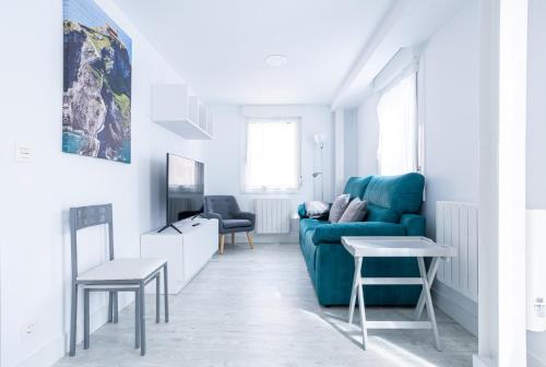 salon z niebieską kanapą i stołem w obiekcie El Ancla de Bermeo By Urdaibai Rentals w mieście Bermeo