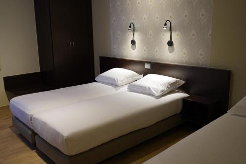 a bedroom with two beds and two lights on the wall at Hotel Corner House by WP Hotels in Blankenberge