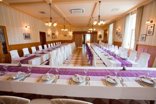 a row of tables in a room with white chairs at Göcsej Palatinus Étterem és Panzió in Zalaegerszeg