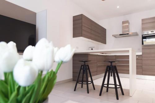 a kitchen with stools and a counter with white flowers at Origer Apartments by Rentaroo in Luxembourg