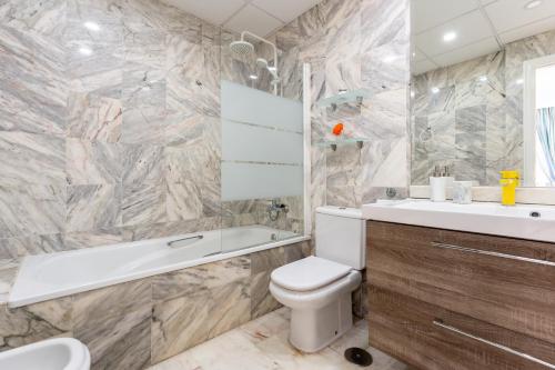 W łazience znajduje się biała toaleta, wanna i umywalka. w obiekcie Doña Sofía w mieście Fuengirola