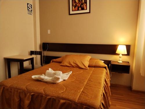 Un dormitorio con una cama con una toalla. en Hotel Dubái, en Tacna