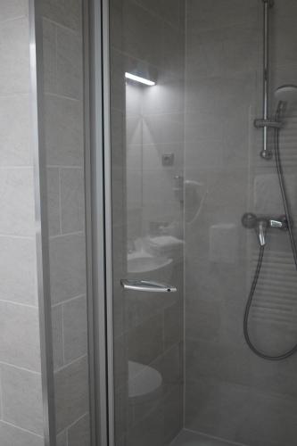 een douche met een glazen deur in de badkamer bij Hotel Corner House by WP Hotels in Blankenberge