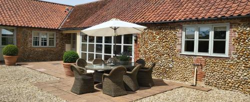 a patio with a table and chairs and an umbrella at Tern Place in Kelling